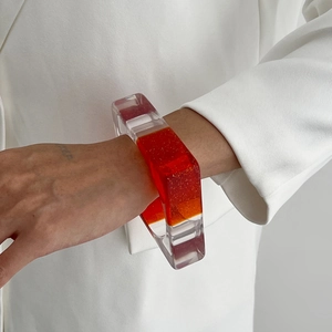 Gros plan d'un bracelet en résine irrégulier avec segments orange et paillettes dorées