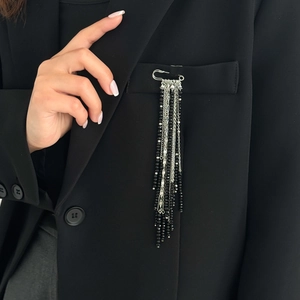 Détail d'une broche argentée avec pompons en perles de cristal noir sur costume