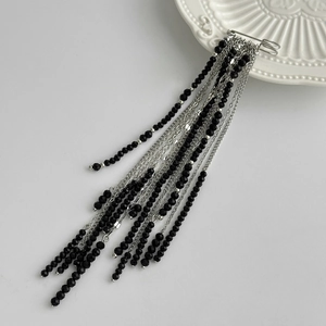 Macro detail of multi-layer black crystal beads and silver tassel chain brooch for suits