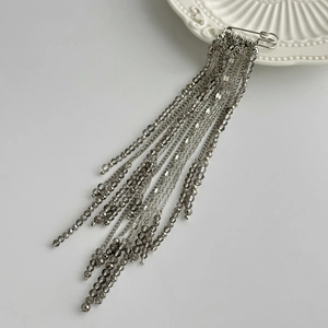 Close-up of hip-hop style brooch with dark grey crystal beads and long metallic tassels