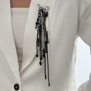 Silver fringe tassel brooch with black beads pinned on a white suit jacket collar