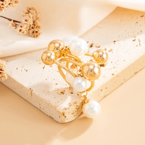Detailed view of layered gold pearl ring on a textured stone and silk fabric background