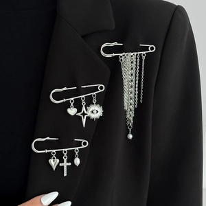 Spille argentate con ciondoli a cuore e croce e nappe di perle su un blazer nero