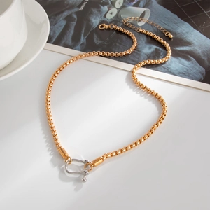 Detail showing two-tone gold and silver rolo chain with a U-shaped metal pendant charm
