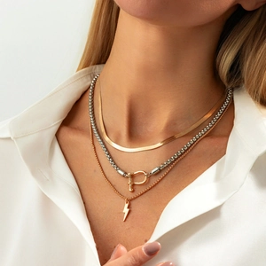 Detailed layered look of gold snake chain with horseshoe clasp and lightning bolt pendant