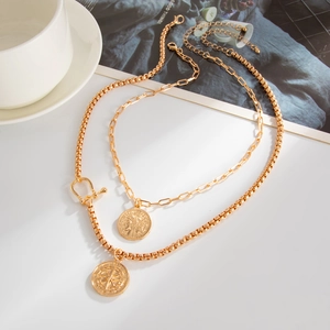 Detail of double-layered gold necklace with coin pendant and adjustable lobster clasp
