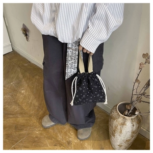 Detail of black corduroy bucket bag with white heart floral print and drawstring closure