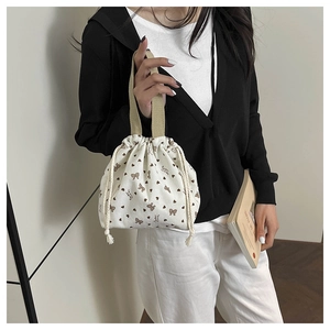 Detailed texture of corduroy bag with heart and bow patterns held by a model