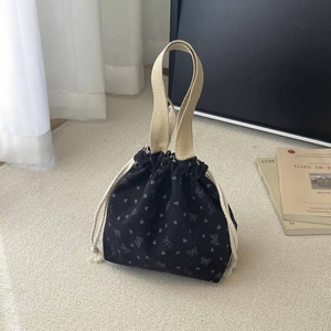 Detailed shot of black corduroy drawstring bag with butterfly and heart patterns