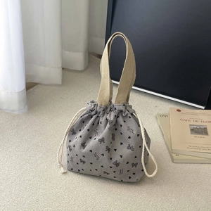 Detail of gray corduroy bucket bag featuring heart patterns and soft drawstring closure