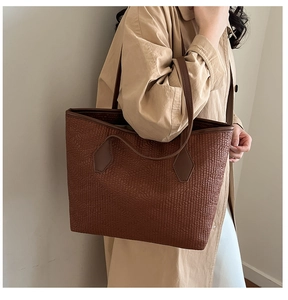 Détail du sac cabas marron avec motif cuir gaufré porté sur un manteau beige chic