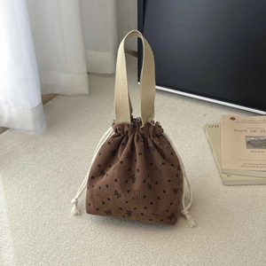 Detail of brown corduroy bucket bag with heart floral prints and white cotton drawstring