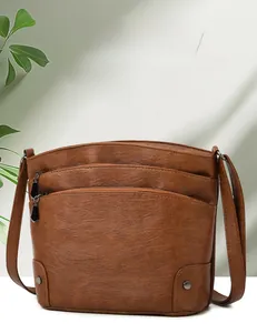 Detail of dark brown faux leather shoulder bag with multi-zipper pockets and rivet decor
