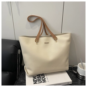 Detail of minimalist tote bag showing cream faux leather texture and gold hardware