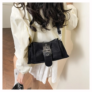 Détail du sac bandoulière noir avec large sangle décorative à boucle et œillets en métal