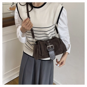 Détail d'un sac bandoulière en daim marron café avec sangle en cuir et boucle métallique