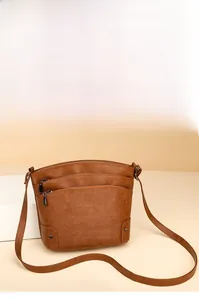 Detail of brown leather bucket bag with triple zipper pockets and pebble texture