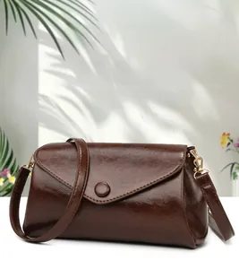 Detail of vintage brown shoulder bag in glossy oiled leather with gold-tone hardware
