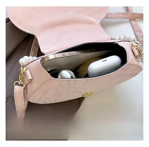 Pink pearl-embellished crossbody bag interior showing phone and earphone storage