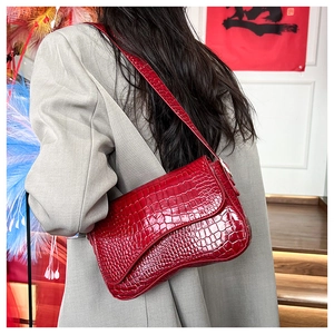 Red glossy crocodile texture crossbody bag detail on a model in gray blazer suit
