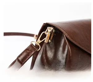 Close-up of golden metal buckle and durable shoulder strap on vintage brown leather bag