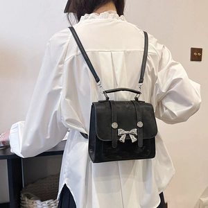Mini sac à dos élégant en daim noir avec boucle nœud argentée porté par un mannequin chic