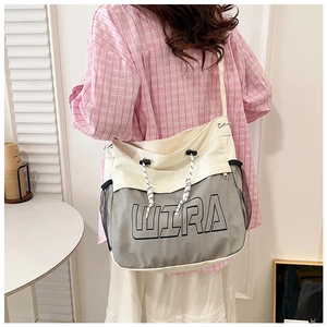 Detail of white canvas tote bag with WIRA print, mesh panels and striped shoulder strap