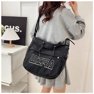 Close-up of black mesh tote bag with white ULTRA print and adjustable shoulder strap