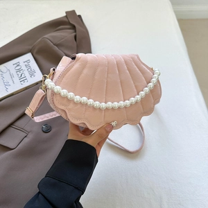 Pink shell-shaped handbag with pearl handle and stylish pleated texture on a soft background