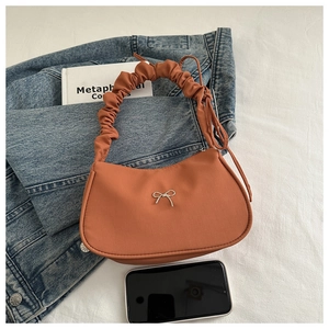 Vue détaillée du sac caramel avec poignée plissée et ornement de nœud en métal argenté