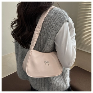 Détail du sac à bandoulière rose avec un nœud argenté et une sangle matelassée