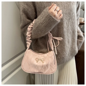 Close-up of pink ruched cloud bag with golden bow hardware and pleated handle details