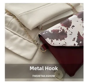 Detail of high-quality gold metal hook and cow print pattern on a burgundy leather bag