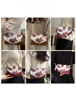 Detailed view of women's cow print envelope bag with gold chain and flap closure