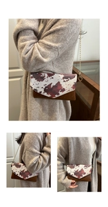 Close-up of a stylish crossbody envelope bag with brown cow print and golden chain strap