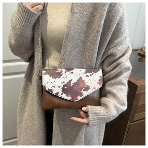 Detail of crossbody envelope bag with animal print texture and gold chain strap