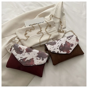 Detail of cow print patchwork flap bags in burgundy and brown with chain straps