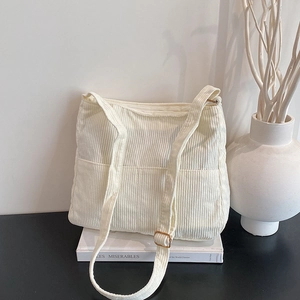 Chic beige corduroy tote bag with dual front pockets and adjustable shoulder strap