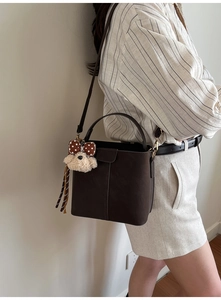 Detail der dunkelbraunen Vintage-Beuteltasche mit Plüschhund-Anhänger und Schultergurt