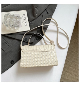 Detail shot of beige woven leather handbag with metallic protective feet and top handle