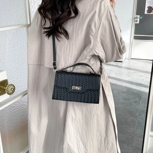 Borsa a tracolla nera intrecciata minimalista con fibbia dorata su modella in trench