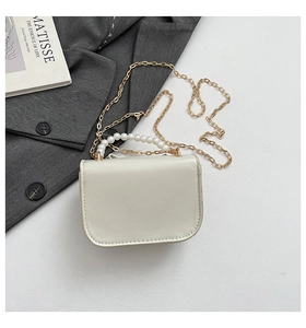 Detail showing creamy white faux leather mini bag with pearl handle and golden chain strap