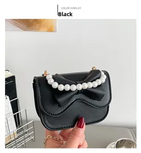 Close-up of black matte leather mini bag with decorative bow and pearl handle detail