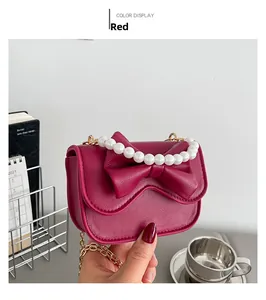 Detail of red rose handbag with pearl handle, bow design and lychee leather texture