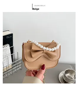 Close-up of brown handbag featuring a leather bow, pearl handle, and gold chain strap