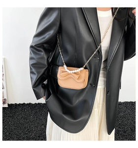Detail of brown mini bag featuring a large bow, pearl handle, and golden chain strap