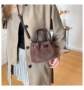 Detail of dark brown suede bucket bag worn with a stylish long khaki trench coat