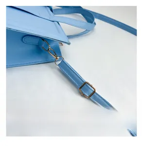 Λεπτομέρεια γαλάζιας τσάντας με χρυσά μεταλλικά κουμπώματα και ρυθμιζόμενο δερμάτινο λουρί