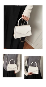 Detail of white patent leather handbag with gold hardware and envelope flap design