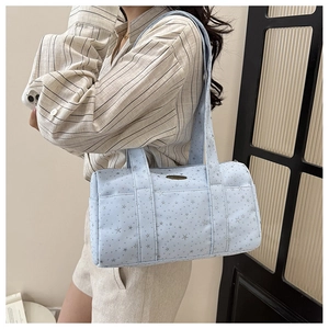 Side view of light blue star pattern cylindrical shoulder bag on model with metal plate